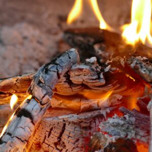 Detailed shot of burning firewood with glowing embers and flames, creating a warm ambiance.